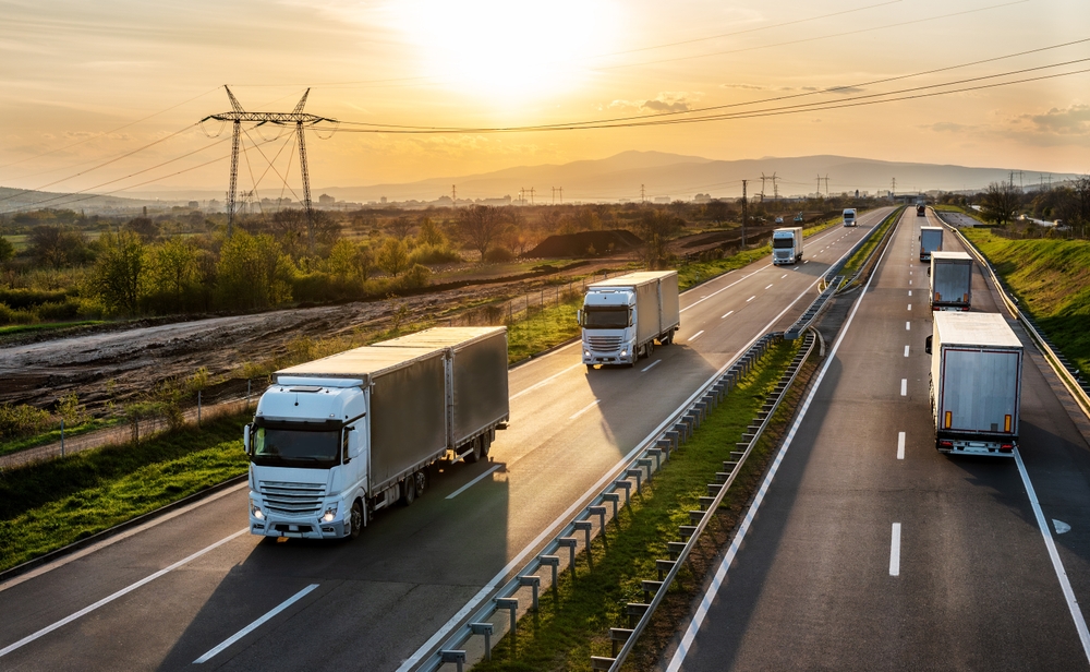 Big,White,Transportation,Trucks,With,Grey,Containers,Passing,Other,Trucks