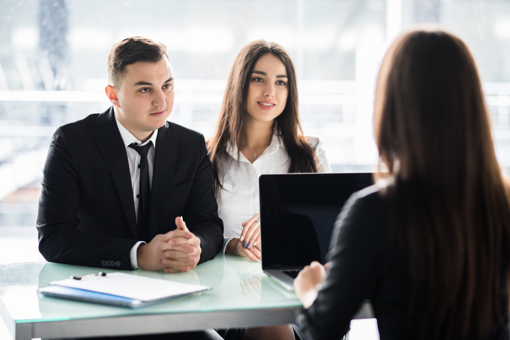 Saleswoman,Talking,With,A,Couple,Of,Happy,Customers,Sitting,In